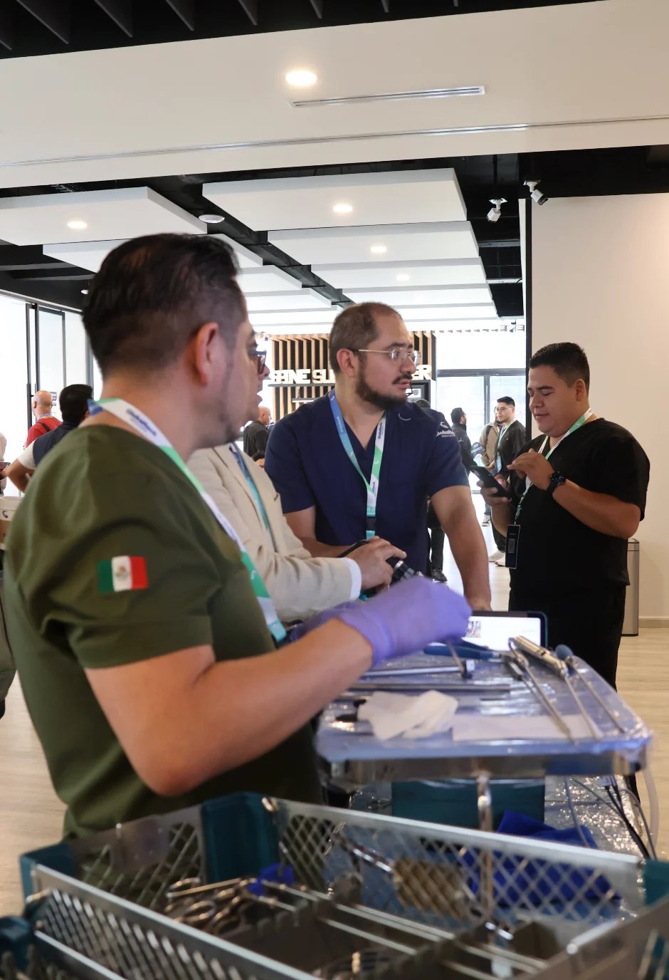 Profesionales del sector salud con gafetes observando material médico sobre una mesa en un evento