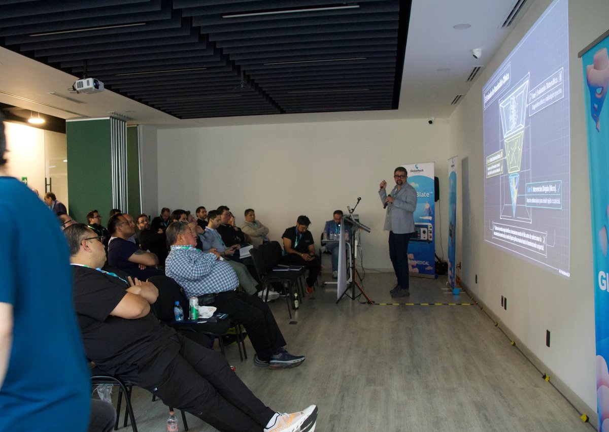 Grupo de profesionales sentados en una sala de conferencias observando una presentación en una pantalla grande